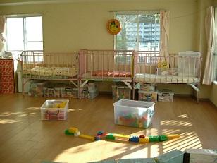 柵がついたベットやブロッグの玩具などがある乳児の部屋の写真