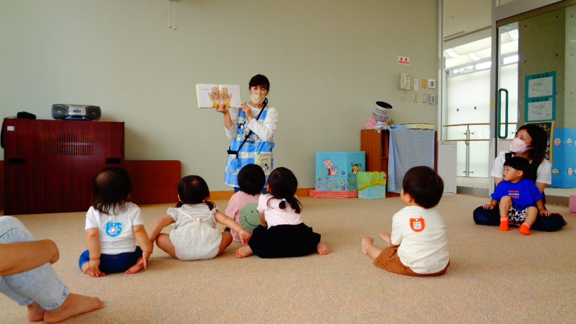 パンダの着ぐるみ姿の人が背負っている箱に玉入れをする親子の様子の写真